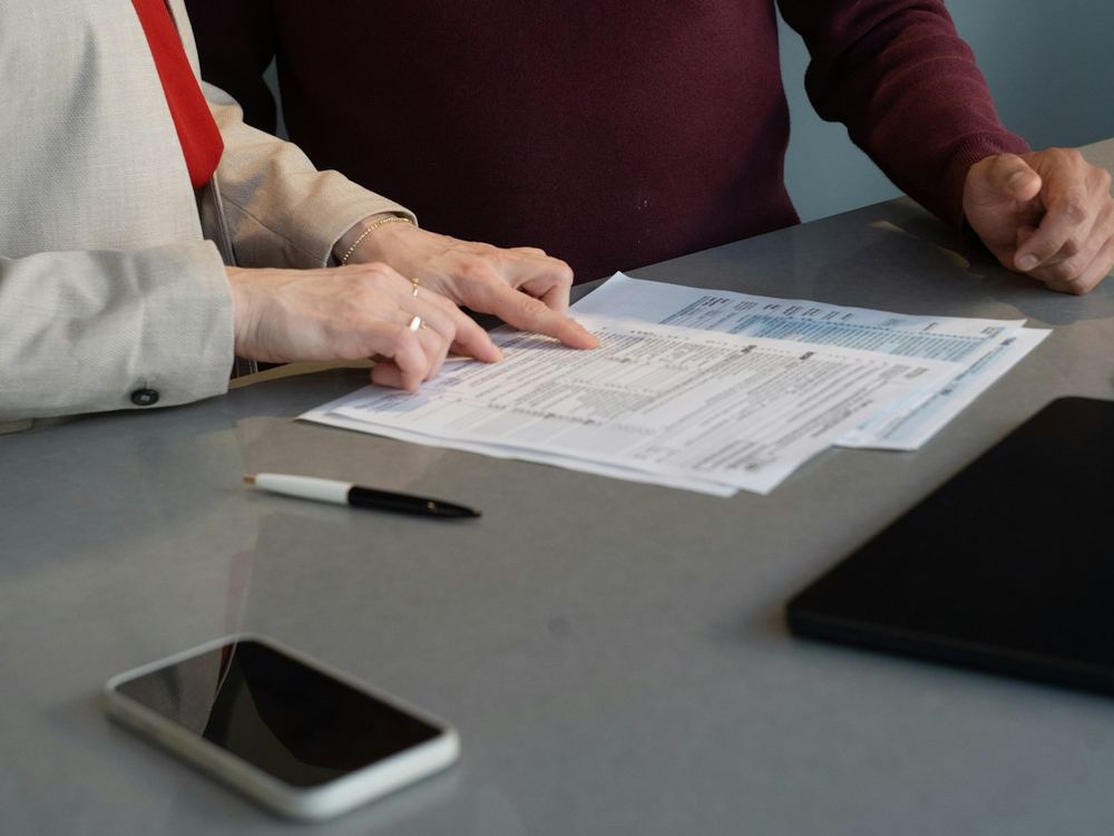 Dos personas revisando juntas unos documentos sobre una mesa